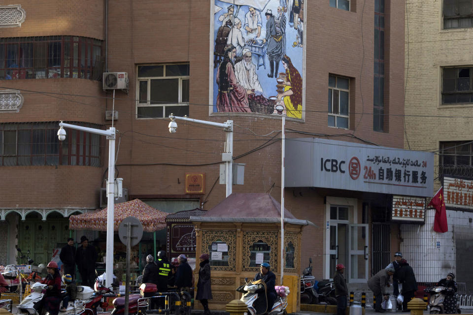 FILE - In this Nov. 5, 2017, file photo, residents pass by a security checkpoint and surveillance cameras mounted on a street in Kashgar in western China's Xinjiang region. The Chinese database Victor Gevers found online was not just a collection of old personal details. The discovery by Gevers, a Dutch cybersecurity researcher who revealed it on Twitter last week, has given a rare glimpse into China’s extensive surveillance of Xinjiang, a remote region home to an ethnic minority population that is largely Muslim. The area has been blanketed with police checkpoints and security cameras that apparently are doing more than just recording what happens. The database Gevers found appears to have been recording people’s movements tracked by facial recognition technology, he said, logging more than 6.7 million coordinates in a span of 24 hours. (AP Photo/Ng Han Guan, File)