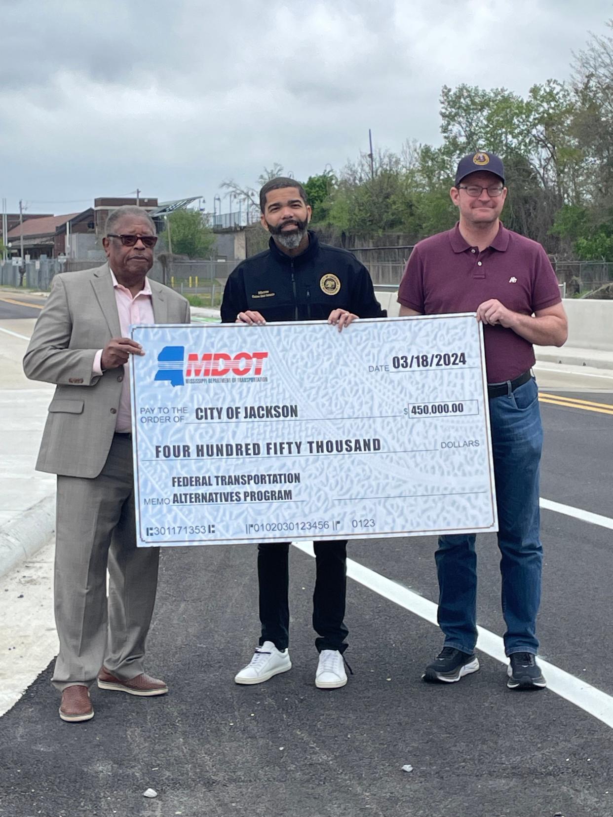 From left: Central District Transportation Commissioner Willie Simmons, Jackson Mayor Chokwe Antar Lumumba and City Engineer Robert Lee pose with a $450,000 check to repair sidewalks in-front of the Medgar and Myrlie Evers Home National Monument on Monday, March 25.