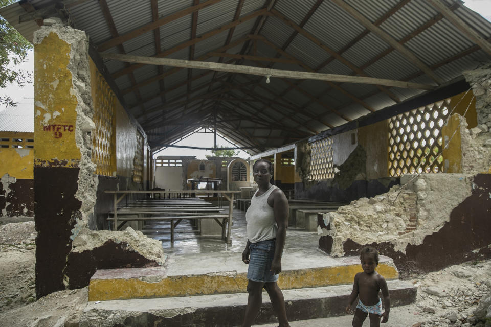 Porceus Vethal and her daughter walk past the ruins of the Saint-Helene chapel destroyed by last year's 7.2-magnitude earthquake, in the area of Labore in Les Cayes, Haiti, Thursday, Aug. 18, 2022. Residents have complained that no government official had visited them despite repeated promises that they would come to help. (AP Photo/Odelyn Joseph)