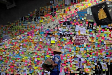 FILE PHOTO: A worker walks past Post-it notes bearing messages left behind on the walls of the Legislative Council, a day after protesters broke into the building, in Hong Kong