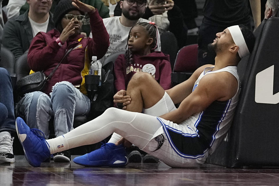 Orlando Magic guard Jalen Suggs holds his leg after being injured during the first half of the team's NBA basketball game against the Cleveland Cavaliers, Wednesday, Dec. 6, 2023, in Cleveland. (AP Photo/Sue Ogrocki)