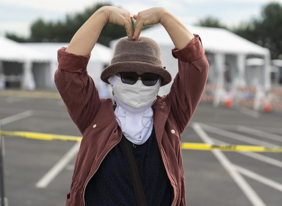 Orange County resident Esther Song expresses her gratitude with a "Love" gesture after getting her vaccine at the Disneyland Resort serving as a Super POD (Point Of Dispensing) COVID-19 mass vaccination site Wednesday, Jan. 13, 2021, in Anaheim, Calif. The parking lot is located off Katella Avenue and sits southeast of Disneyland. California is immediately allowing residents 65 and older to get scarce coronavirus vaccines, Gov. Gavin Newsom announced Wednesday. (AP Photo/Damian Dovarganes)