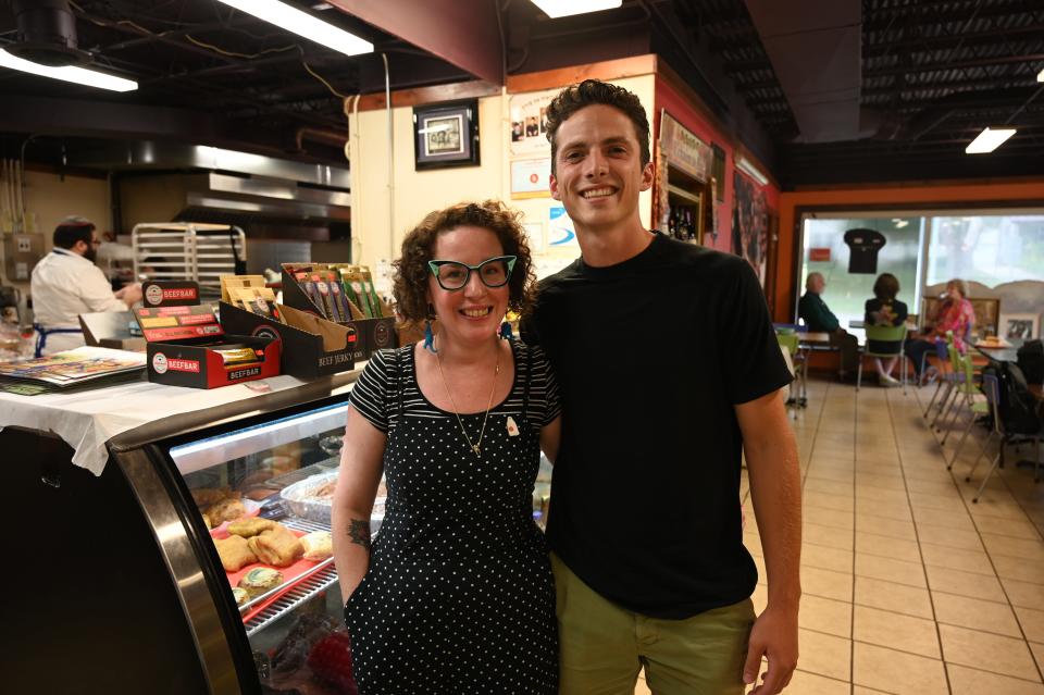 Sarah Booz, left, and Jack Payette pose in front of the deli counter at Maccabee's Kosher Deli in Des Moines. The pair went viral  in late July for creating TikTok videos about the deli.