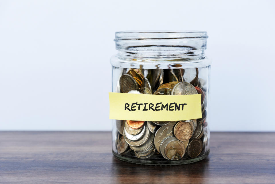 Glass jar filled with coins labeled "RETIREMENT" against a plain background