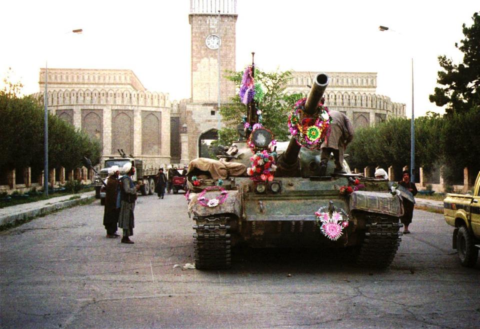 FILE - In this Sept. 28, 1996 file photo, tanks manned by Taliban fighters and decorated with flowers are seen in front of the the damaged Presidential palace in Kabul, Afghanistan. The Taliban fighters who rolled into Afghanistan's capital and other cities in recent days appear awestruck by the towering apartment blocks, modern office buildings and shopping malls. When the Taliban last seized power, in 1996, the country had been ravaged by civil war and the capital was in ruins. (AP Photo/ B.K.Bangash, File)