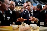 French President Emmanuel Macron eats cheese during a visit to the 57th International Agriculture Fair (Salon international de l'Agriculture) at the Porte de Versailles exhibition center in Paris