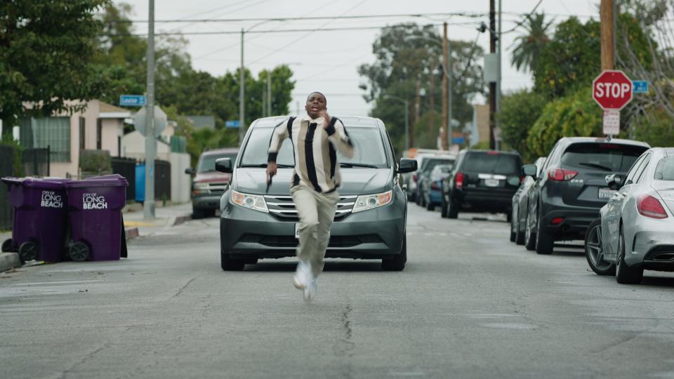 Vince Staples running with a gun down a street