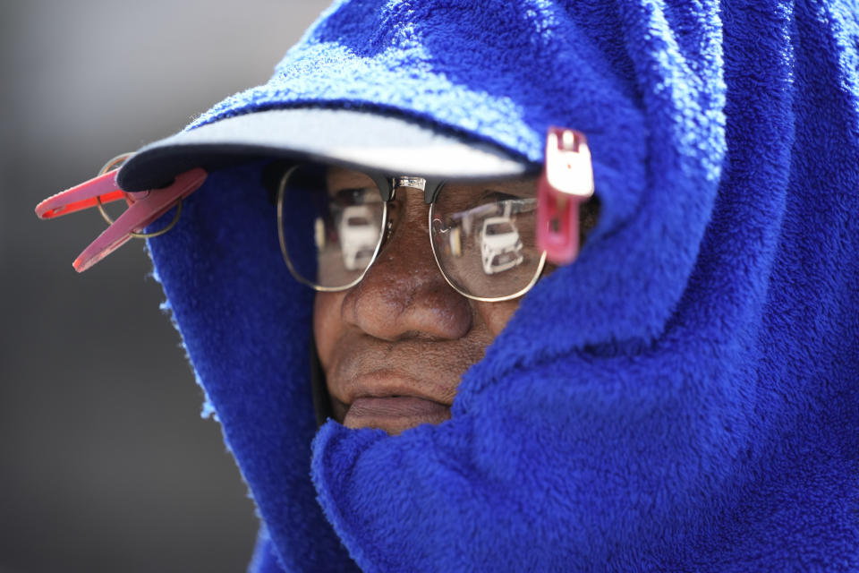 Parking attendant Andy Tinto uses laundry clips to put a blue towel over his cap to protect him from the sun as he assists cars in Manila, Philippines on Monday, April 29, 2024. Millions of students in all public schools across the Philippines were ordered to stay home Monday after authorities cancelled in-person classes for two days as an emergency step due to the scorching heat and a public transport strike. (AP Photo/Aaron Favila)