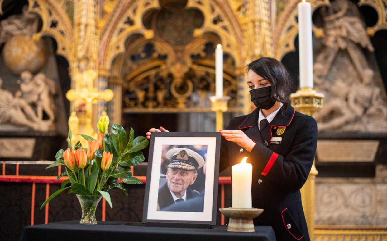 Rosa Wlodarczyk adjusts a photograph of the Duke displayed alongside the nave at Westminster Abbey, which has been dressed in black to mark his death