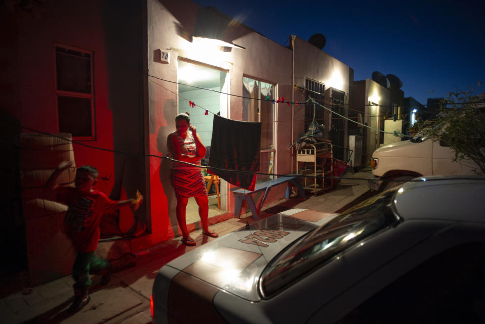 In this June 19, 2019, photo, Ruth Aracely Montoya watches her children play from the entrance to their home in Tijuana, Mexico. After fleeing violence in El Salvador, the family is among 60,000 U.S. asylum seekers returned to Mexico to wait while their claim makes its way through the U.S. court system. (AP Photo/Gregory Bull)