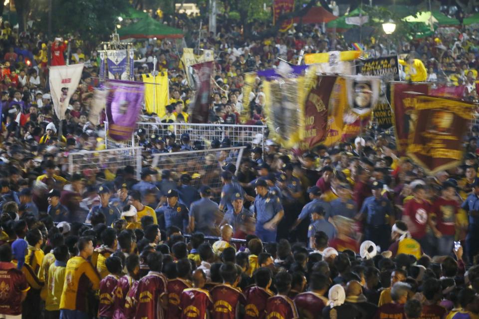 Filipino Roman Catholic devotees topple the barrier to get closer to the image of the Black Nazarene to celebrate its feast day Monday, Jan. 9, 2017 in Manila, Philippines. The raucous celebration drew tens of thousands of devotees in a barefoot procession for several hours around Manila streets and end up with several people injured. (AP Photo/Bullit Marquez)