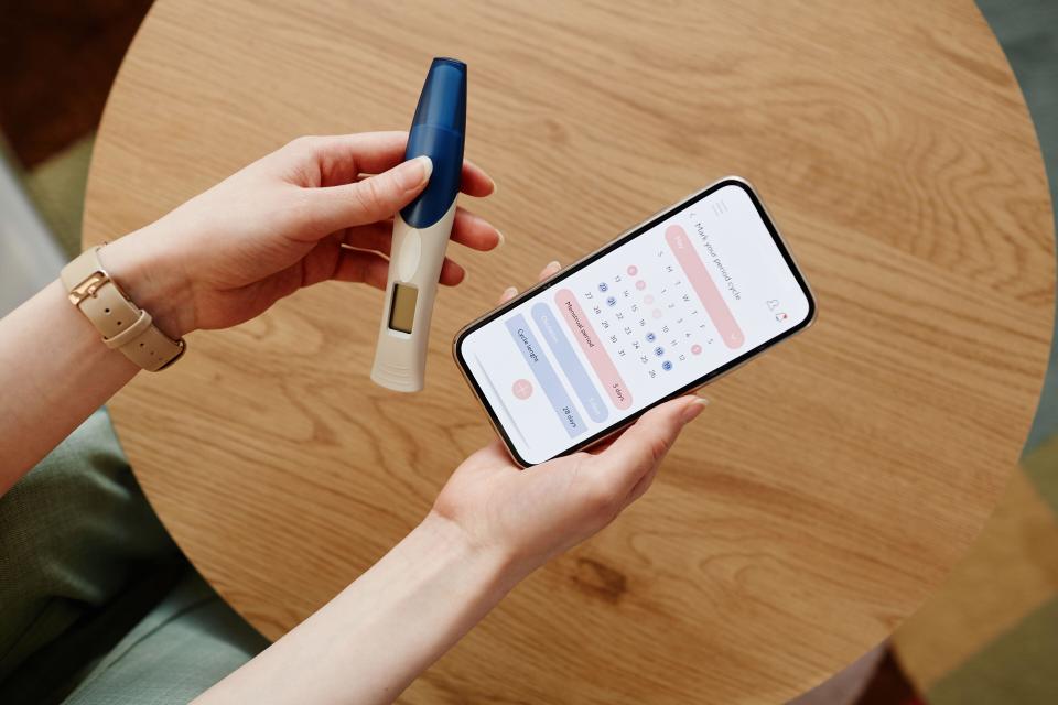 A woman using a mobile app and holding a pregnancy test