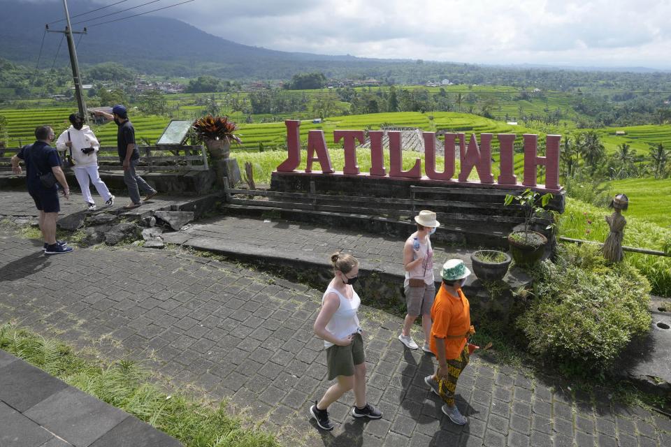 Tourists walk near rice fields irrigated by a traditional terrace system called a "subak" in Jatiluwih in Tabanan, Bali, Indonesia, Monday, April 18, 2022. Bali faces a looming water crisis from tourism development, population growth and water mismanagement, experts and environmental groups warn. While water shortages are already affecting the UNESCO site, wells, food production and Balinese culture, experts project these issues will worsen if existing policies are not equally enforced across the entire island. (AP Photo/Tatan Syuflana)