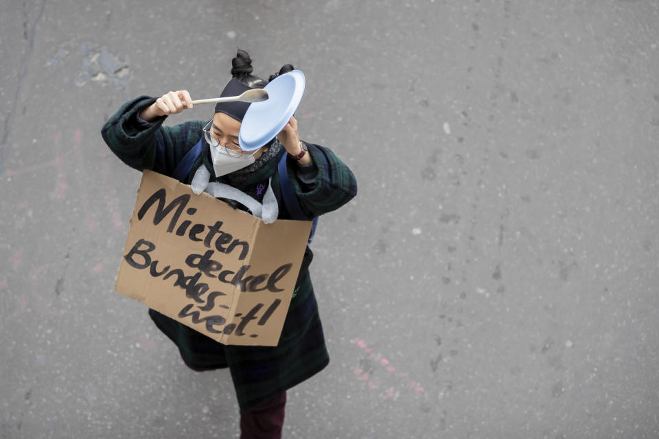 A protester with sign reading "Rent cap nationwide!" during a mass rally to protest against a court ruling removing a rent cap in Berlin, Germany Thursday April 15, 2021. The alliance "Together against displacement and #Mietenwahnsinn" gathered Thursday to protest after the court overturned the rent cap. (Christoph Soeder/dpa via AP)