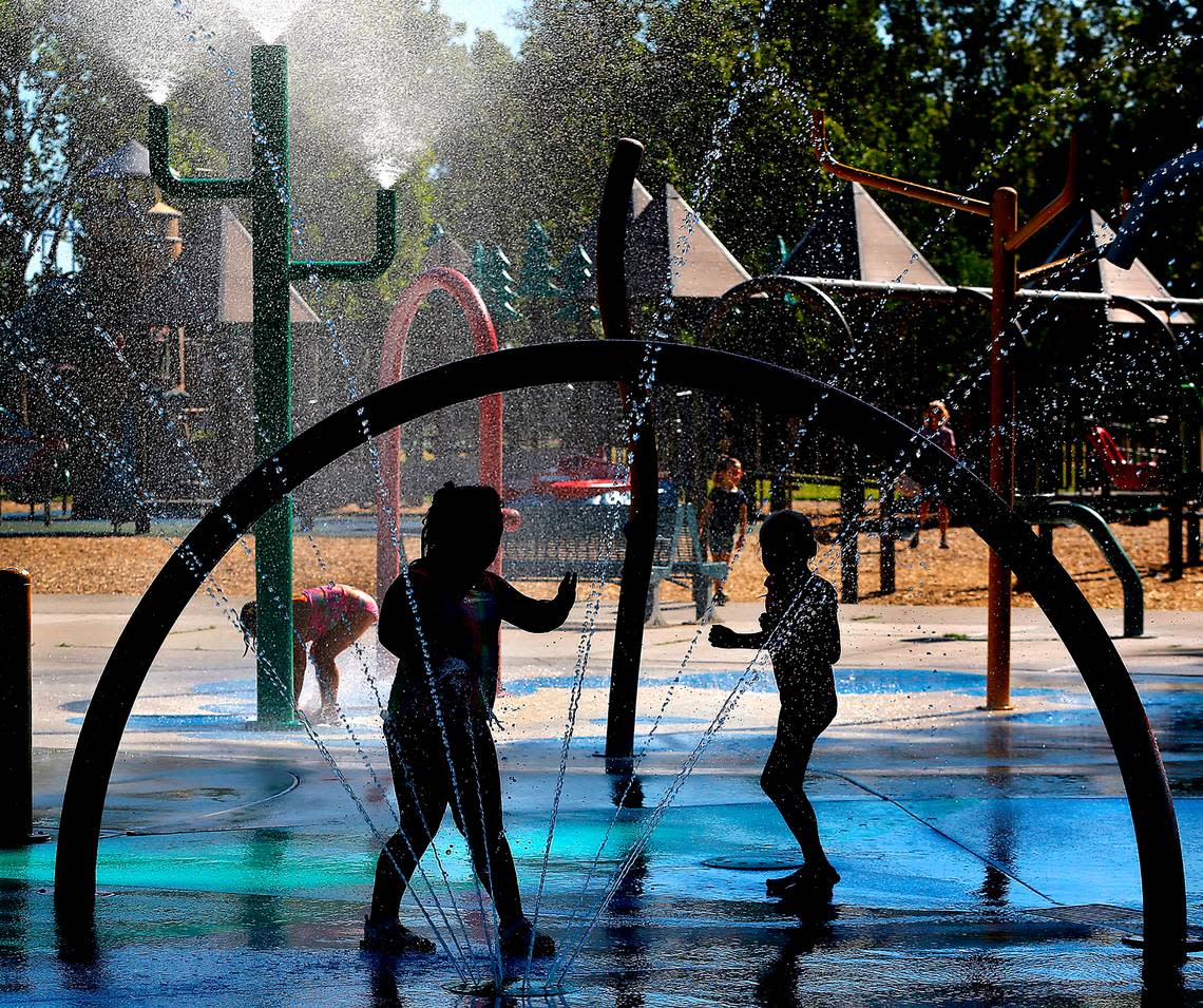 Children play in the shaded area of the splash park near the Playground of Dreams early Thursday. More hot, sunny and summer weather is forecast by the National Weather Service next week, including for Columbia Cup hydroplane racing events.