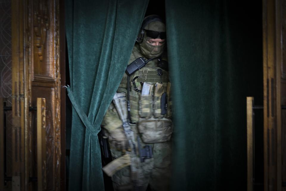 A Russian soldier steps through a curtained opening at the Philharmonic Chamber in Mariupol, in the territory which is under the control of the Government of the Donetsk People's Republic, in eastern Ukraine, Sunday, June 12, 2022. This photo was taken during a trip organized by the Russian Ministry of Defense. (AP Photo)