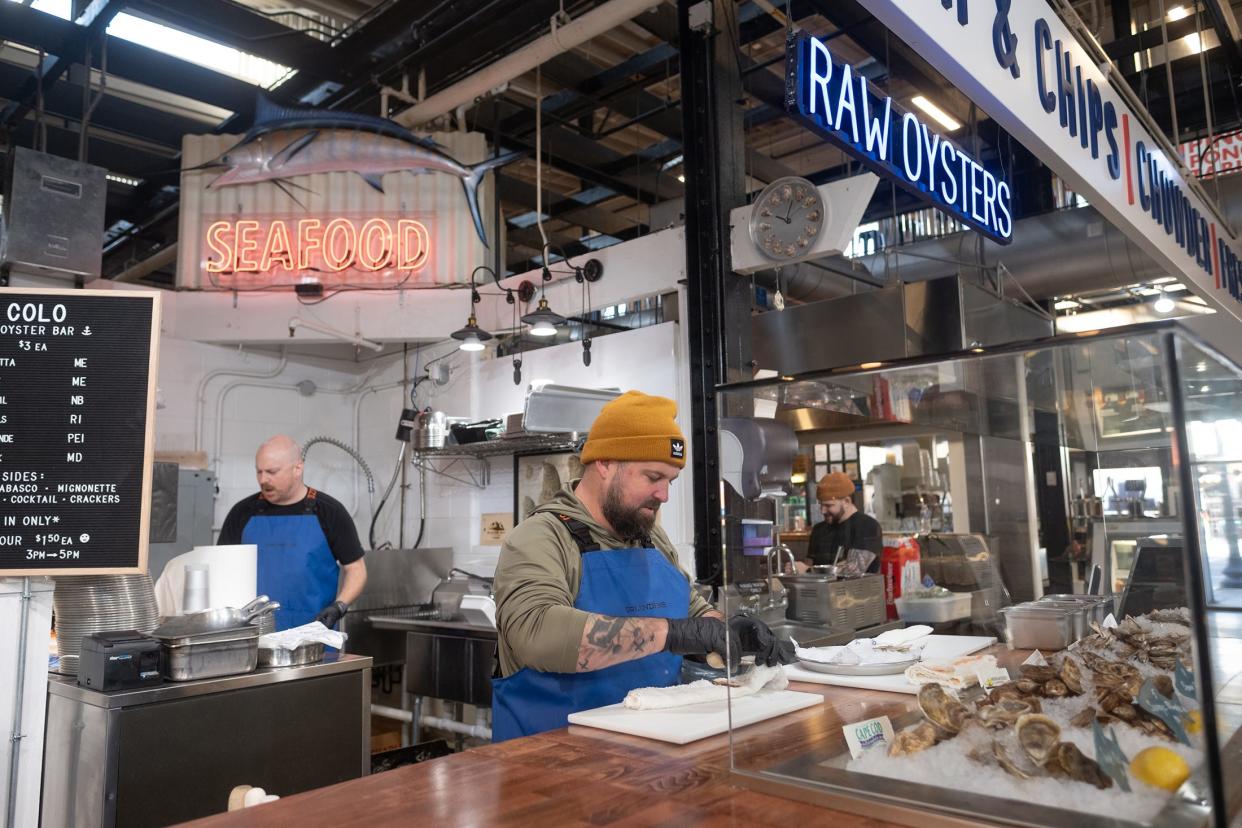 Ian Holmes shucks oysters at COLO Market & Oyster Bar in North Market Downtown.