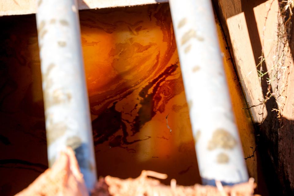 Oil can be seen in a drain's flowing water Wednesday near the site of an 88,000 gallon oil spill. Workers are flushing the drains with fresh water to remove the oil from that system.