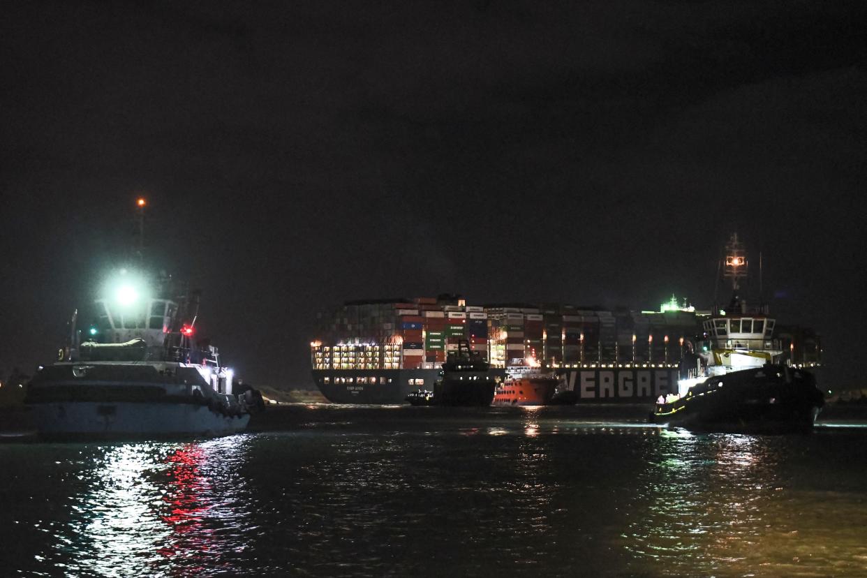 This picture taken late on March 27, 2021, shows a view of tugboats by the Panama-flagged MV Ever Given (operated by Taiwan-based Evergreen Marine) container ship, which has been wedged diagonally across the span of the canal about six kilometers north of the Suez Canal's entrance by the Red Sea port city of Suez since March 23, blocking the waterway in both directions.