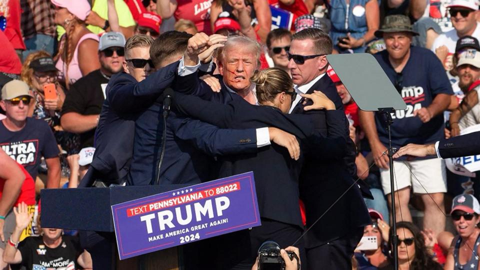 PHOTO: Republican candidate Donald Trump is seen with what appears to be blood on his face surrounded by secret service agents as he is taken off the stage at a campaign event in Butler, Pennsylvania, July 13, 2024. (Rebecca Droke/AFP via Getty Images)