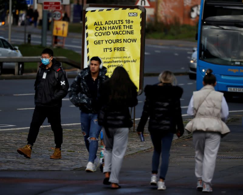 FILE PHOTO: People walk past a sign encouraging the public to get their COVID-19 vaccine doses in Manchester
