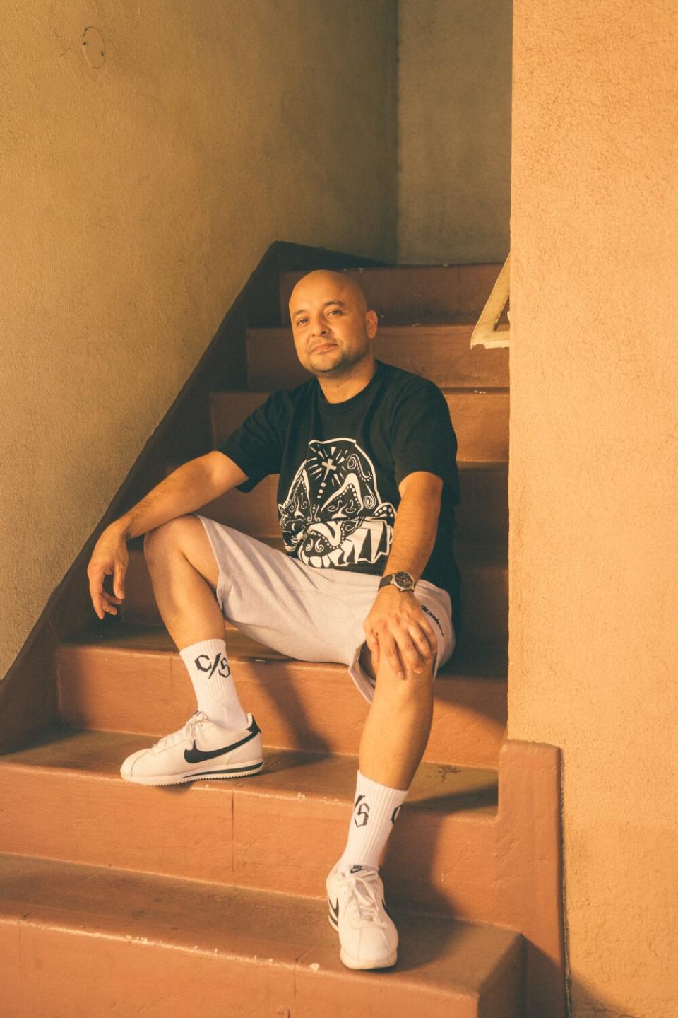 A man sits on some steps in a stairwell while smiling at the camera