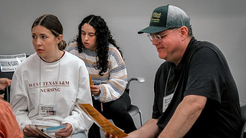 WT nursing students Stephanie Unger, left, and Dafne Fernandez, along with Midland College's Dr. William Christopher Brown, chair of the English and Language Arts department, learn about the roles they will play in WT Nursing's poverty simulation Oct. 11.