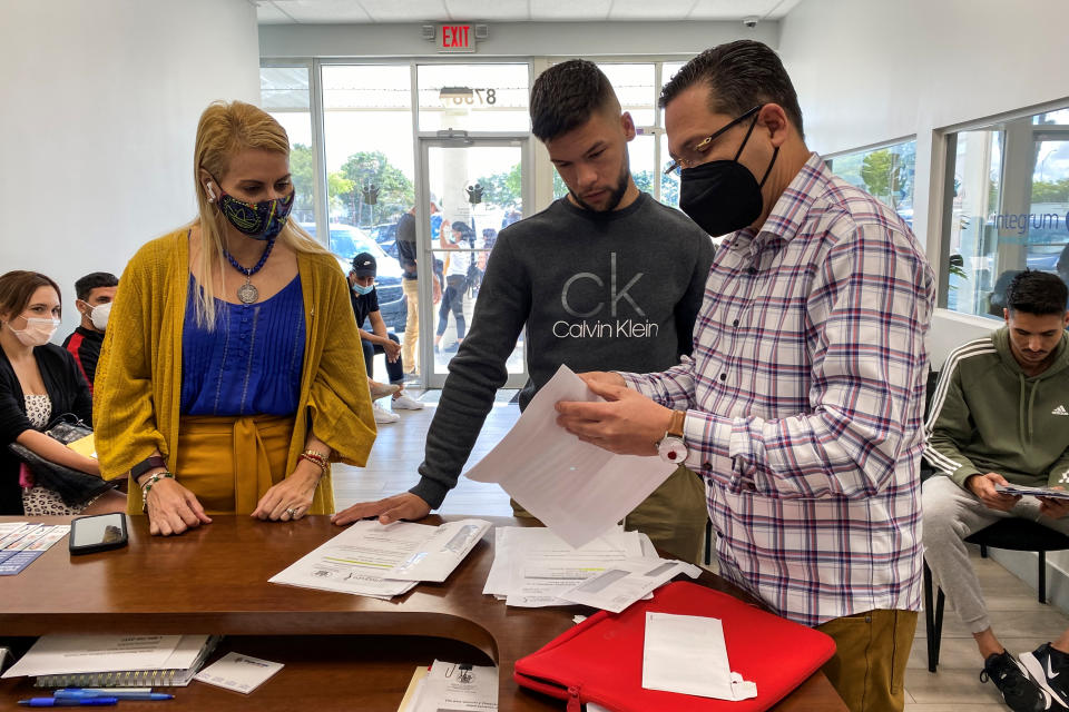 Oasis Pena, left, and Dr. Raul Gonzalez, right, help a migrant at the Integrum Medical Group in Miami on April 18, 2022. (Carmen Sesin / NBC News)
