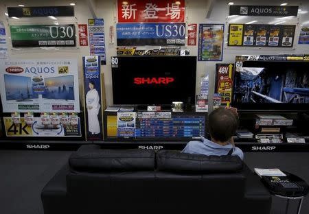 A man sitting on a sofa looks at a Sharp Corp's Aquos TV at an electronics retailer in Tokyo, Japan, June 23, 2015. REUTERS/Yuya Shino