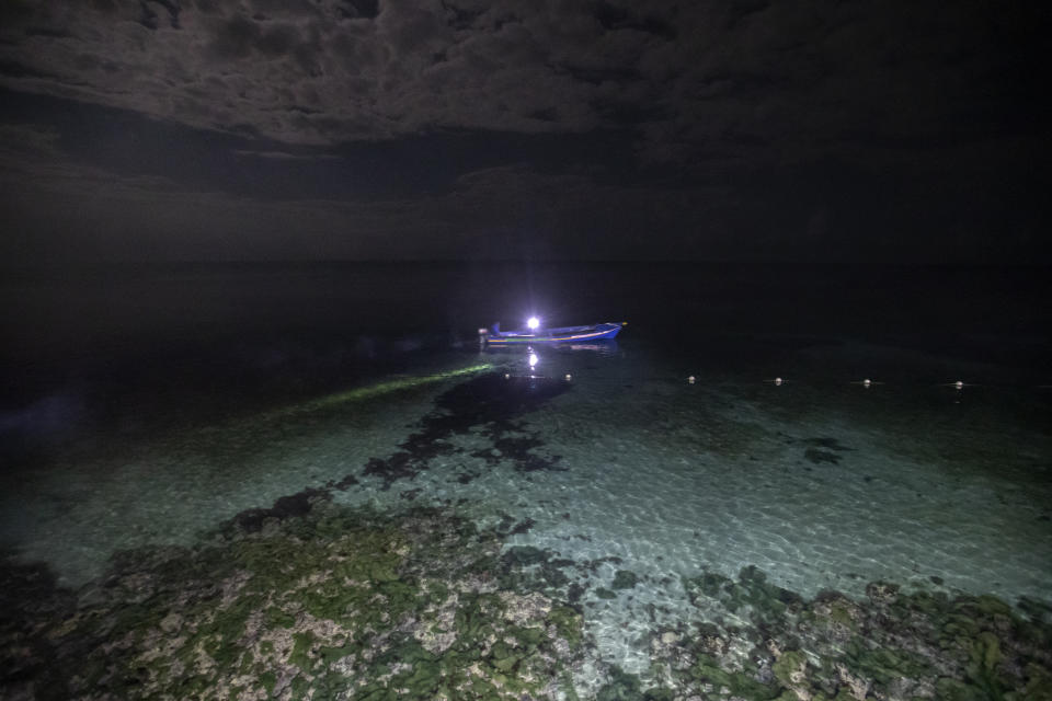 White River Fish Sanctuary wardens Mark Lobban, left, and Donald Anderson patrol the no-take zone for illegal fishermen under moonlight in Ocho Rios, Jamaica, Saturday, Feb. 16, 2019. Spearfishing at night in Jamaica is illegal, especially in the sanctuaries set up to protect the island's endangered coral reefs and replenish fish stocks. (AP Photo/David Goldman)