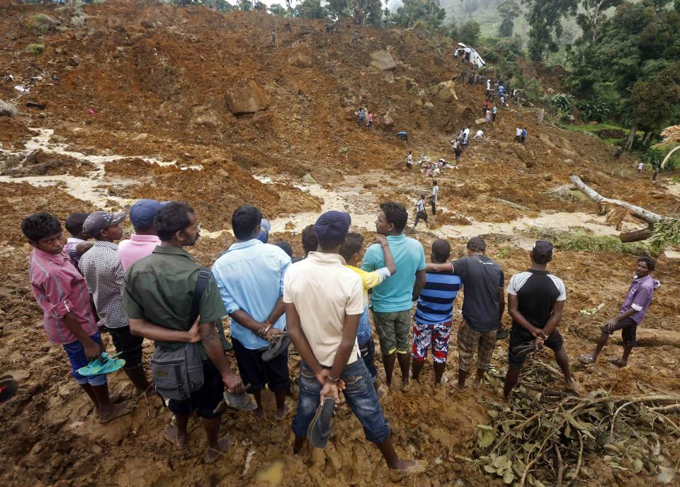 Group of men stand above the site of a landslide at the Koslanda tea plantation near Haldummulla