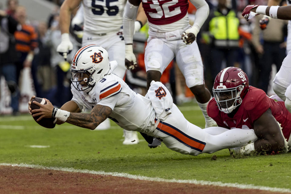 FILE - Auburn quarterback Robby Ashford (9) scores a touchdown on a run as Alabama defensive lineman Jaheim Oatis (91) tries to tackle him during the first half of an NCAA college football game, Saturday, Nov. 26, 2022, in Tuscaloosa, Ala. Auburn opens their season at home against UMass on Sept. 2.(AP Photo/Vasha Hunt)