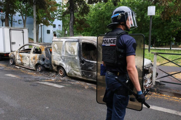 Un oficial de policía francés hace guardia junto a vehículos quemados durante una noche de enfrentamientos entre manifestantes y policías, luego de la muerte de un adolescente de 17 años en Nanterre, suburbio de París, Francia