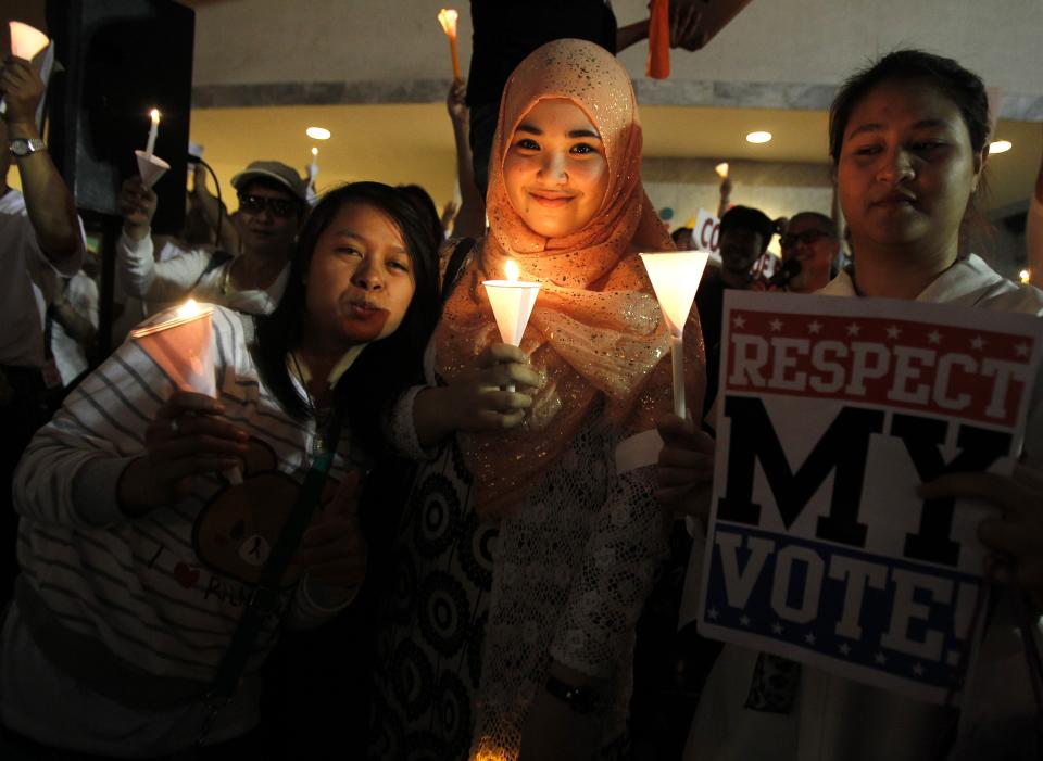 People hold candles and a placard during an anti-violence campaign in central Bangkok January 10, 2014. Thailand on Friday played down talk of a military coup ahead of a planned "shutdown" of the capital next week by protesters trying to overthrow Prime Minister Yingluck Shinawatra and said life would go on much as normal. REUTERS/Chaiwat Subprasom (THAILAND - Tags: POLITICS CIVIL UNREST)