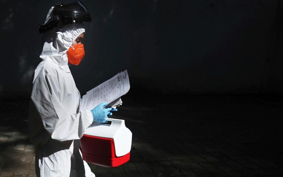 Healthcare worker Lupita Cruz carries a cooler filled with COVID-19 test samples, at the Angela Peralta Theater in Mexico City - AP