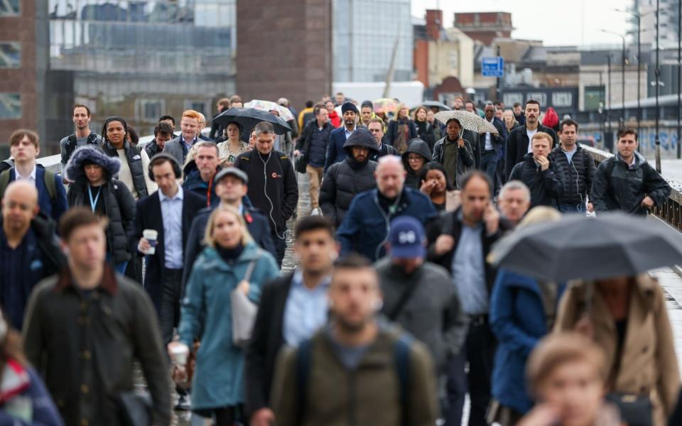 Commuters cross London Bridge in the rain