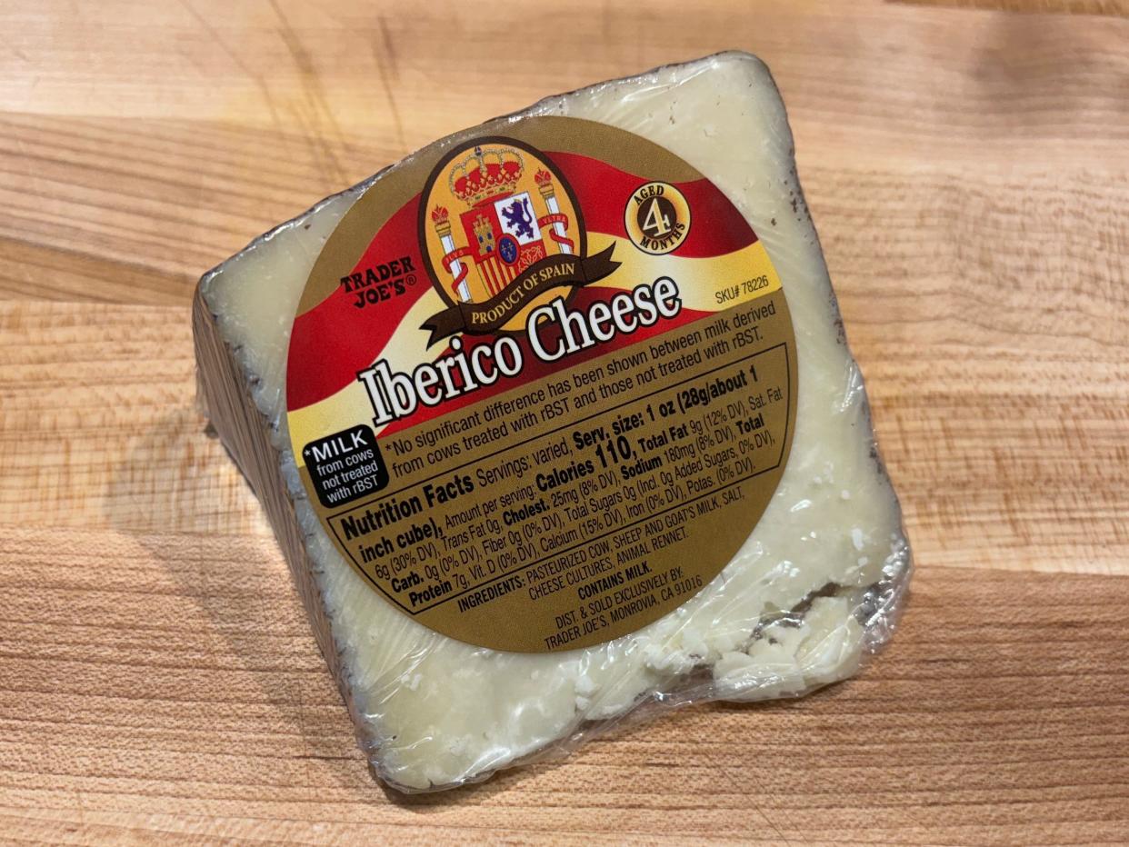 A gray wedge of cheese with gold and red label reading "Iberico cheese"