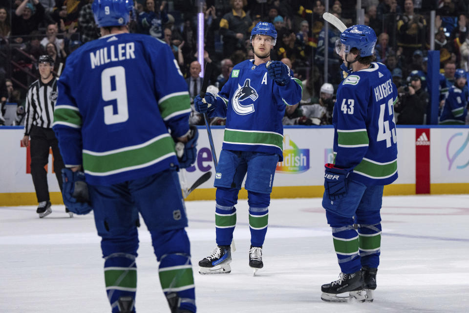 Vancouver Canucks' J.T. Miller (9) and Quinn Hughes (43) skate to Elias Pettersson (40), who scored against the Arizona Coyotes during the first period of an NHL hockey game Thursday, Jan. 18, 2024, in Vancouver, British Columbia. (Ethan Cairns/The Canadian Press via AP)