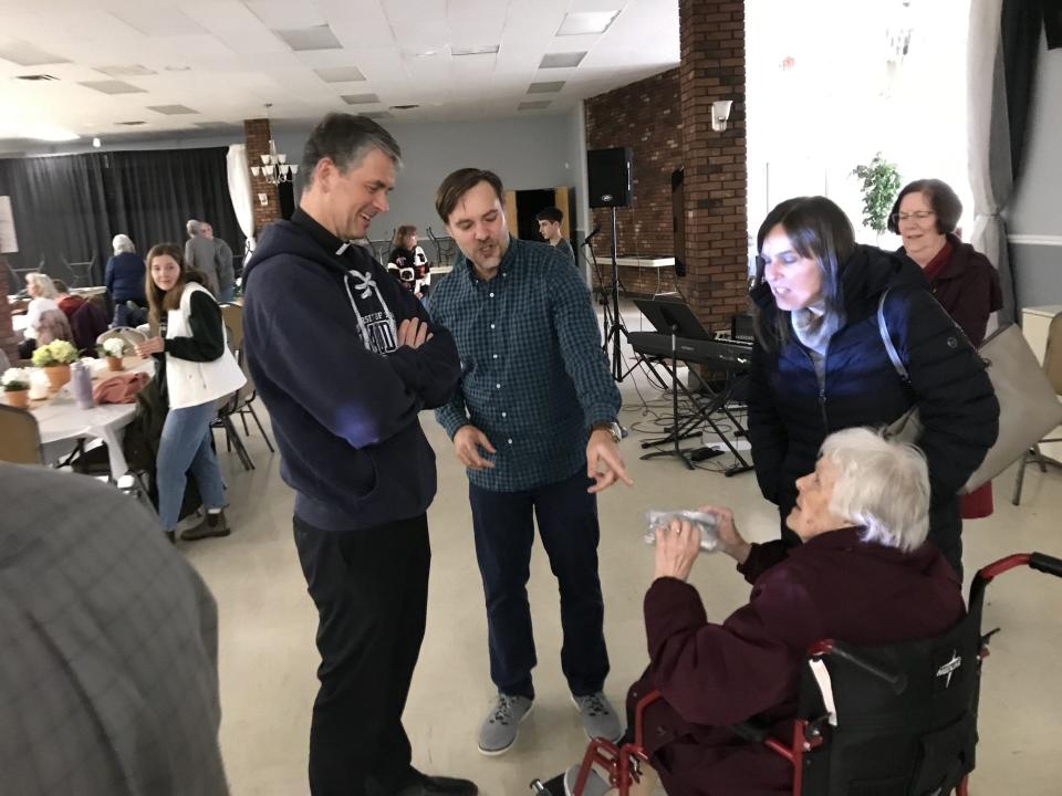 Joe Boggs (second from left) points to a bag of Job's Tears' rosaries that his grandmother, Ruth Masserant, wants to have blessed by Father John Riccardo, a missionary priest who spoke at the conclusion of Project Rescue at the Monroe Knights of Columbus hall Monday night. Assisting Masserant is Lynn Hintz, her daughter.
