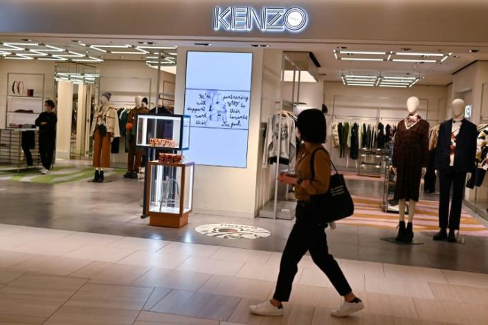 A woman walks past a Kenzo outlet in Tokyo a day after the death of founder Kenzo Takada in Paris aged 81
