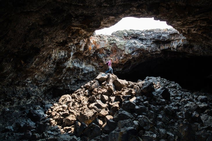 Hiker under the skylight in Indian Tunnel Cave in Craters of the Moon National Monument