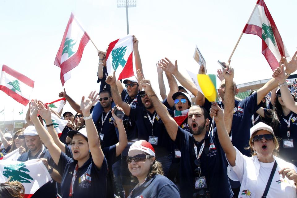 People wave Lebanon flags during a mass headed by Pope Francis at Amman International Stadium