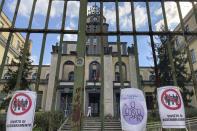 Signs reading in Italian "No gathering" hang from a closed gate of the Cesare Battisti primary school, in Rome, Thursday, March 4, 2021. The first anti-pandemic decree from Italy's new premier, Mario Draghi, tightens measures governing school attendance while easing restrictions on museums, theaters and cinemas. (AP Photo/Gregorio Borgia)