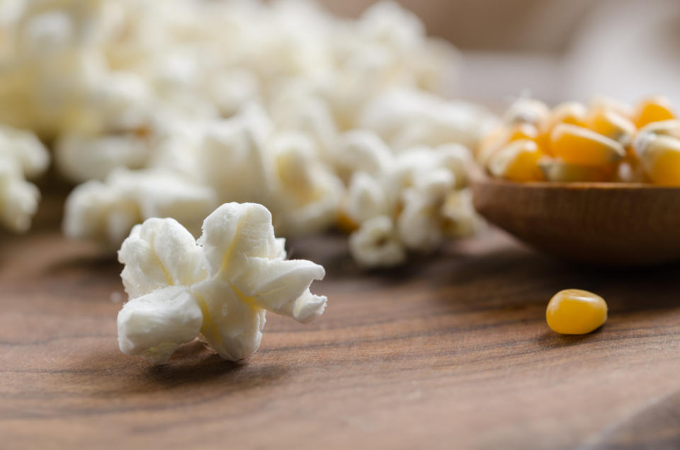 popcorn on a wooden table and a spoonful of corn.macro.