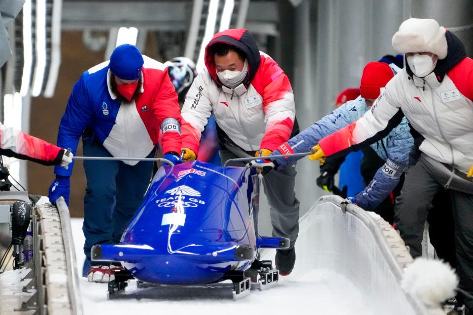 Track assistants push the bobsled of Brad Hall and Nick Gleeson (AP)