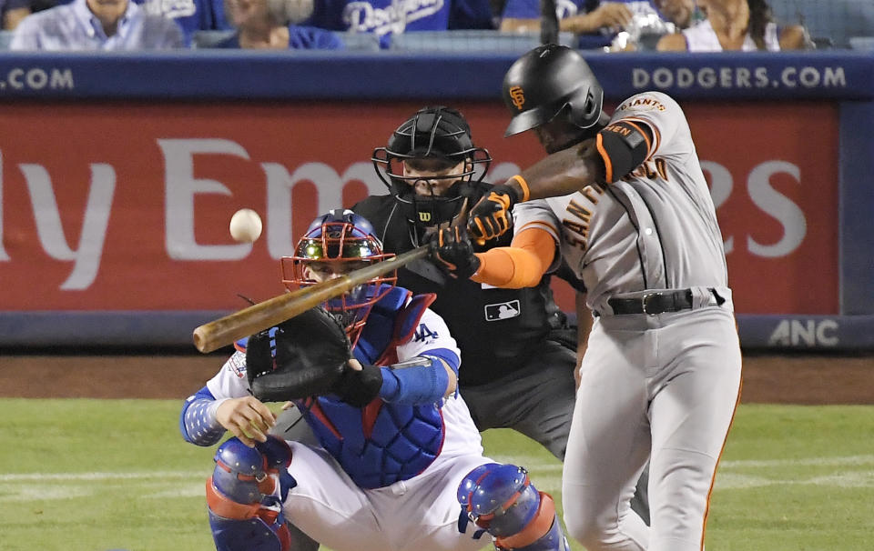 FILE - In this Aug. 15, 2018, file photo, San Francisco Giants' Andrew McCutchen hits a three-run home run as Los Angeles Dodgers catcher Yasmani Grandal and home plate umpire Stu Scheurwater watch during the eighth inning of a baseball game in Los Angeles. The playoff-contending New York Yankees are close to completing a trade for San Francisco Giants outfielder Andrew McCutchen. A person familiar with the negotiations told The Associated Press on Thursday night, Aug. 30, 2018, the Yankees would send infielder Abiatal Avelino and another minor leaguer to San Francisco for McCutchen. The person spoke on condition of anonymity because the deal wasn't finalized. (AP Photo/Mark J. Terrill, File)