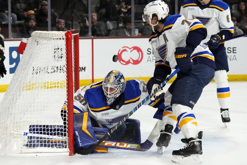 St. Louis Blues goaltender Jordan Binnington looks for the puck after giving up a goal to Arizona Coyotes right wing Christian Fischer as Blues defenseman Justin Faulk, right, skates in late during the first period of an NHL hockey game Tuesday, March 7, 2023, in Tempe, Ariz. (AP Photo/Ross D. Franklin)