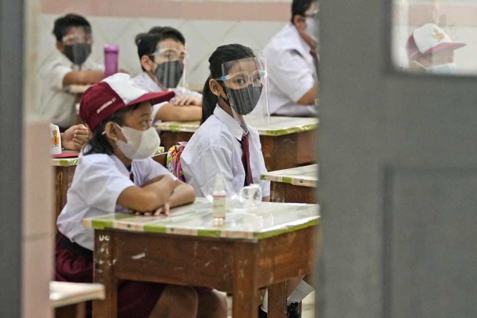 Students wearing face masks to help prevent the spread of COVID-19 attend class during the first day of school reopening at an elementary school in Jakarta, Indonesia, Monday, Aug. 30, 2021. Authorities in Indonesia's capital kicked off the school reopening after over a year of remote learning on Monday as the daily count of new COVID-19 cases in the country continues to decline. (AP Photo/Dita Alangkara)