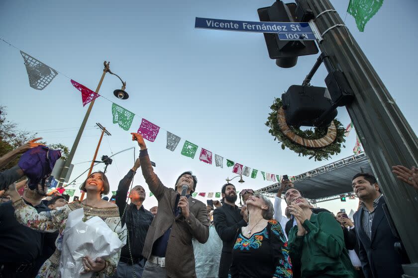 BOYLE HEIGHTS, CA-SEPTEMBER 16, 2022: left to right-Alejandra Fernandez, daughter of the late Mexican ranchera icon Vicente Fernandez, Los Angeles City Councilman Kevin de Leon, Fernadez's window Maria del Refugio Abarca Villasenor, his grandson Vicente Fernandez IV, and granddaughter Sisy Fernandez, react as a cover is removed from a street sign during a ceremony at Mariachi Square in Boyle Heights for the renaming of Bailey Street after Fernandez. He was a cultural legend known as "El Rey," the King of Ranchera. Fernandez passed away on December 12 at the age of 81. (Mel Melcon/Los Angeles Times)