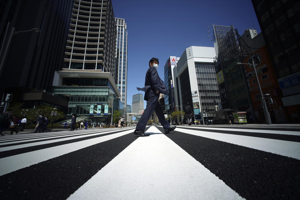 A man with a protective mask to help curb the spread of the coronavirus crosses a pedestrian walkway on Friday, April 10, 2020, in Tokyo. Japanese Prime Minister Shinzo Abe declared a state of emergency last Tuesday for Tokyo and six other prefectures to ramp up defenses against the spread of the coronavirus. (AP Photo/Eugene Hoshiko)